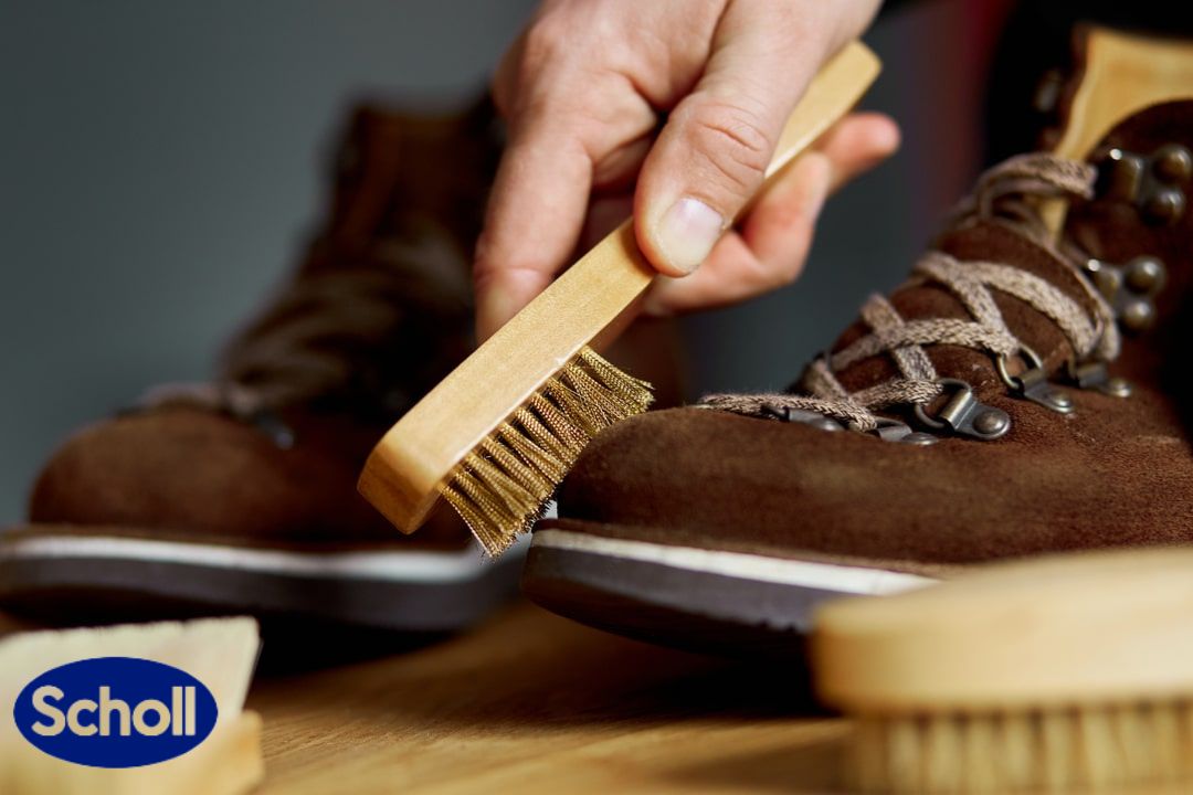 Cipele od prevrnute kože čiste muške ruke sa četkom na drvenoj pozadini.
